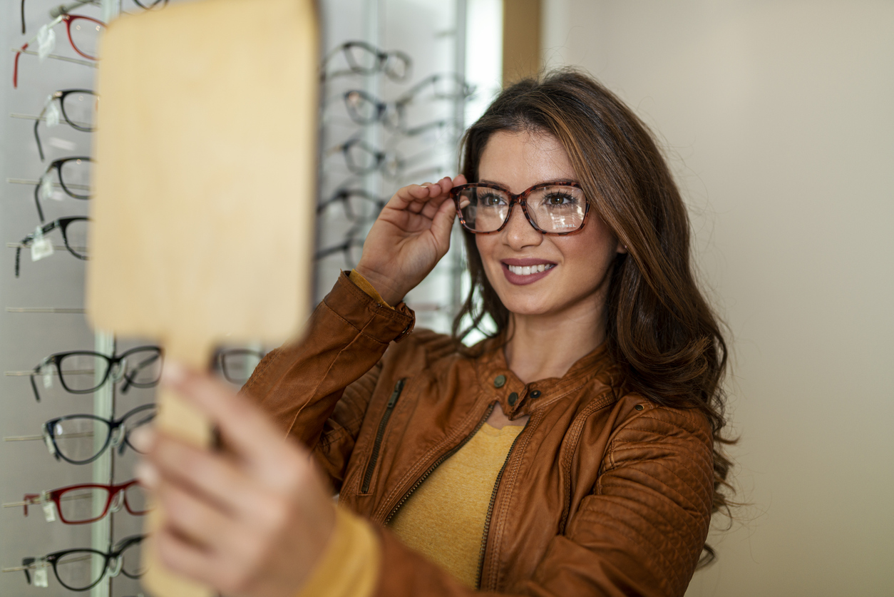 Frau testet die Optik einer Brille mit einem Handspiegel